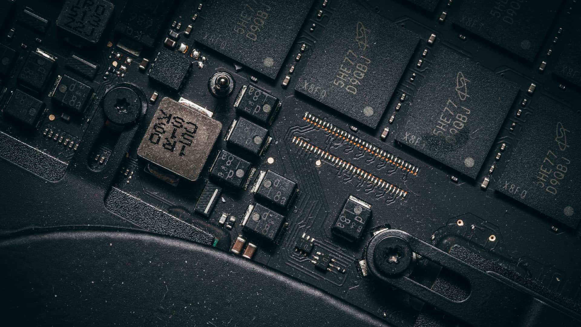 Close-up of a circuit board, its chips and capacitors lit from one side